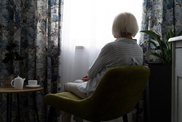 Mujer mayor viendo por la ventana mientras piensa en cuánto se cobra de viudedad 
